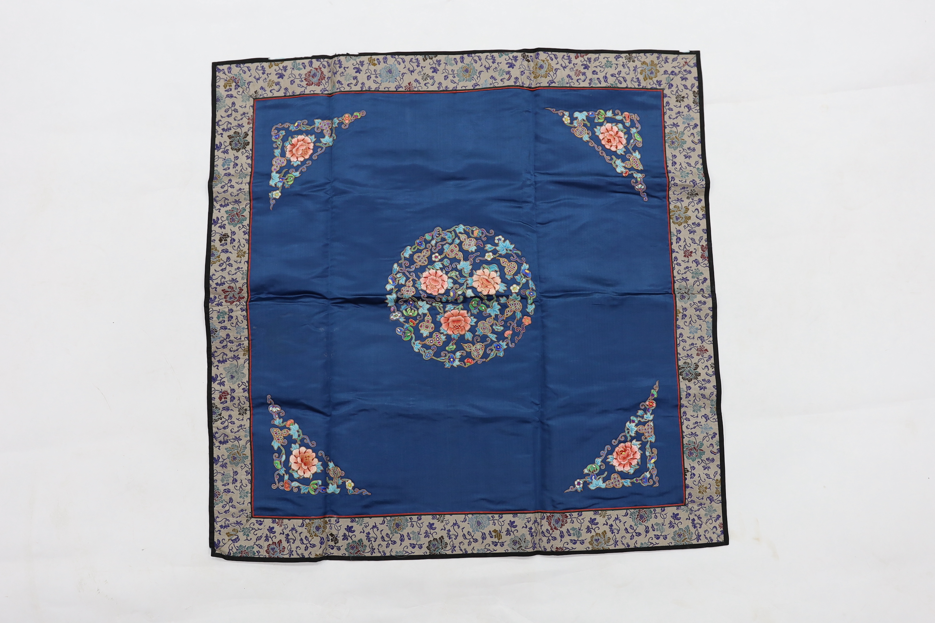 Five Chinese embroidered mats with polychrome silk embroidery using Beijing knot stitch, together with a large square blue silk cover with silk embroidered spot motifs and gold thread work, all items bordered with silk b